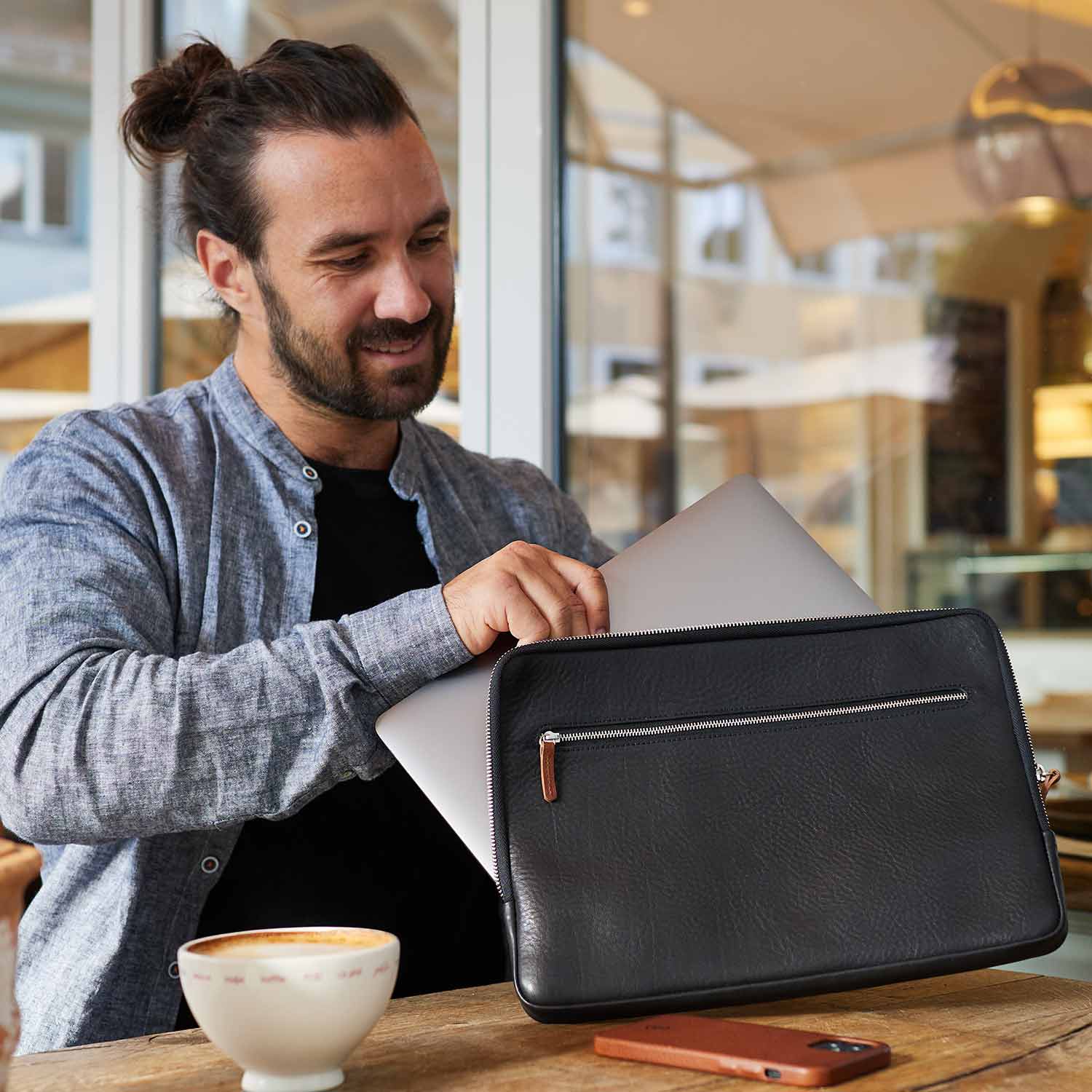Ein Mann steckt ein Surface Pro Laptop in eine schwarze Lederhülle